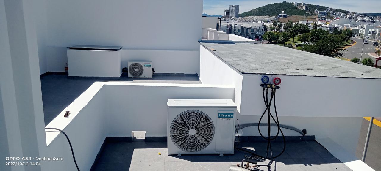 Equipo de aire acondicionado en azotea residencial con cielo despejado en Querétaro, contexto ideal para energía solar.