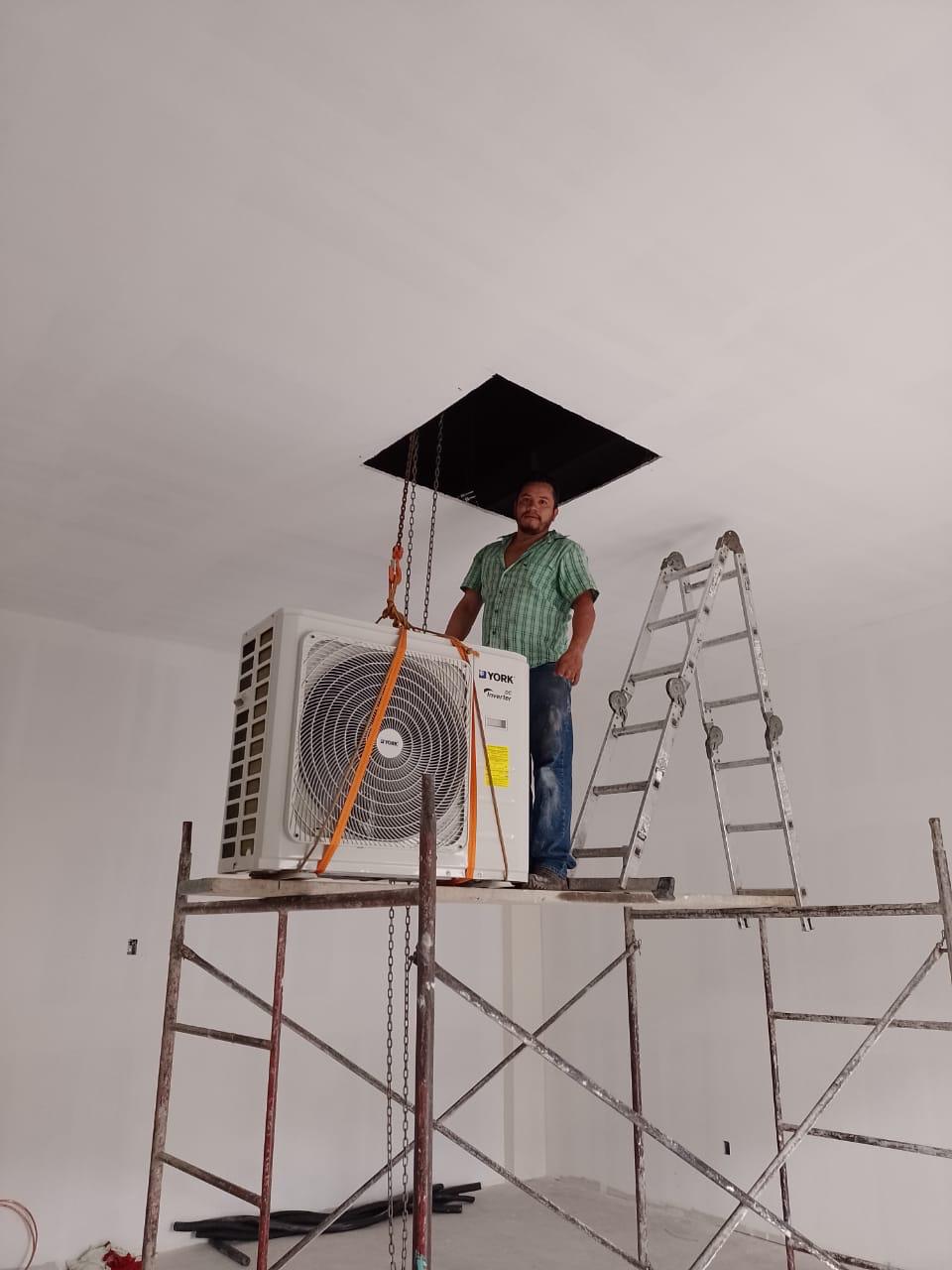 Técnico izando un condensador York con poleas en obra.